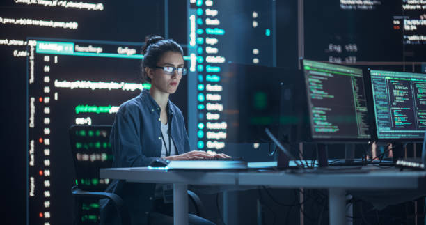 istock Female Programmer Working in Monitoring Control Room, Surrounded by Big Screens Displaying Lines of Programming Language Code. Portrait of Woman Creating a Software. Futuristic Coding Concept. 1518857461