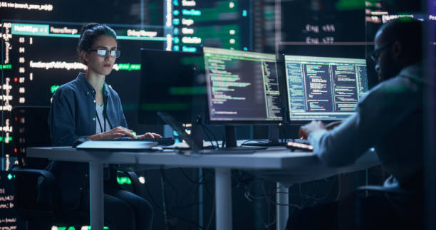 Diverse Young Man and Woman Working on Desktop Computers, Surrounded by Big Screens Displaying Code Prompts. Professional Computer Engineers Developing Autonomous Algorithm for Generative AI. hombres y mujeres jóvenes diversos que trabajan en computadoras de escritorio, rodeados de pantallas grandes que muestran indicaciones de código. ingenieros informáticos profesionales desarrollando algoritmos autónomos para ia generativa.