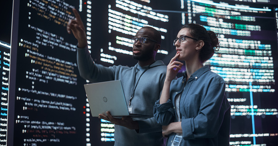 Portrait Of Two Diverse Developers Using Laptop Computer Discussing ...