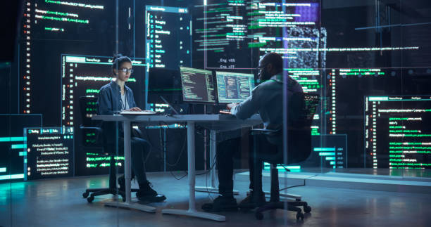 istock Portrait Two Diverse Developpers Working on Computers, Typing Lines of Code that Appear on Big Screens Surrounding Them. Male and Female Programmers Creating Innovative Software Together, Fixing Bugs 1518866525