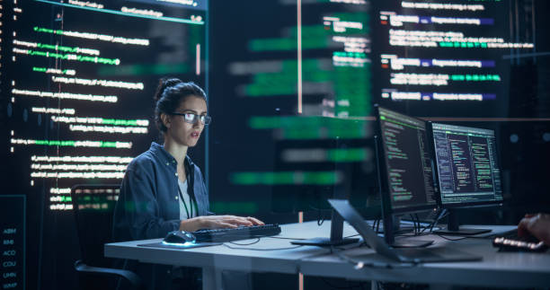 istock Focused Woman Working as a Developer, Surrounded by Big Screens Displaying Lines of Code in a Monitoring Room. Female Programmer Using Desktop Computer, Analysing Data, Creating AI Software 1518867597