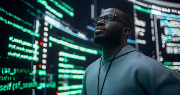 istock Portrait of Worried Professional Programmer Fixing a Bug, Dealing with Crashing System. Young Black Man Looking at Big Digital Screens Glitching While Displaying Code Lines, Thinking of Solutions 1518876073