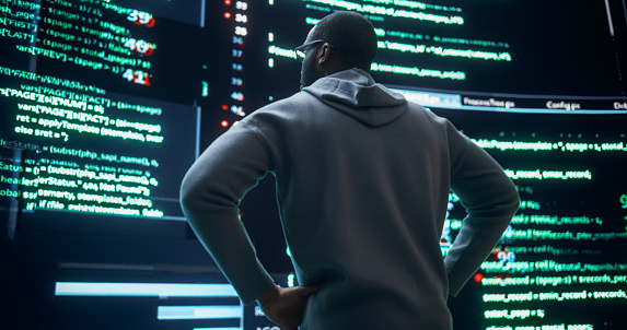 Portrait of Young Black Man Looking at Big Digital Screens Glitching While Displaying Code Lines. Worried Professional Programmer Fixing a Bug, Dealing with Crashing System, Thinking of Solutions