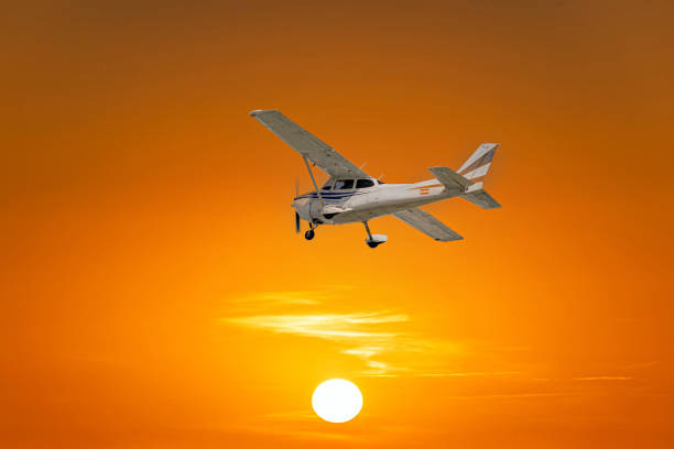 Single engine ultralight airplane flying in the orange sunset sky