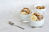 healthy snack with yogurt, chia seeds, banana and walnut in glass, copy space