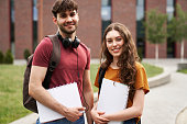 Portrait of two caucasian university students standing outside the university campus