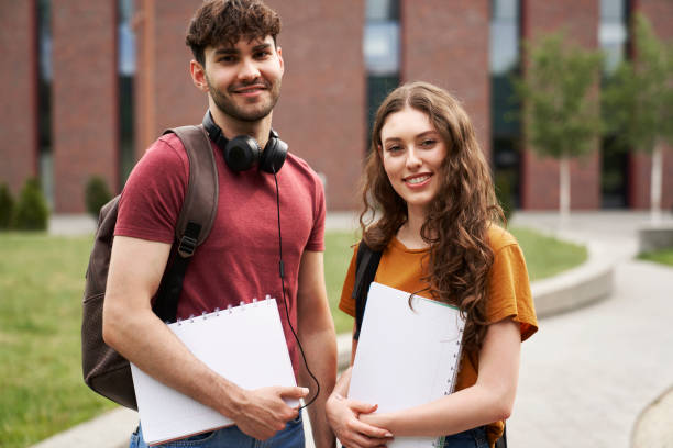 Portrait of two caucasian university students standing outside the university campus stock photo