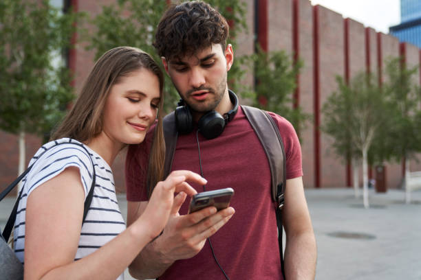 istock Two students browsing mobile phone next to to university campus 1518983429