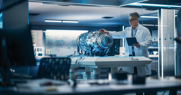istock Jet Engine Specialist Working on a Project with Futuristic Turbine Motor, Standing with Tablet Computer in Scientific Technology Lab. Middle Aged Science Professor Developing a Futuristic Engine 1518995348