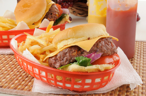 A thick cheeseburger in a basket with fries