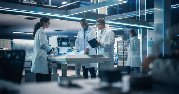 istock Diverse Team of Industrial Robotics Specialists Gathered Around a Table With a Mobile Robot. Engineers In Lab Coats Discussing an Automated Robotic Delivery Assistant with Artificial Intelligence 1519011210