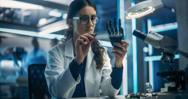 istock Portrait of a Young Female Scientist Working in Technological Research and Development Company, Assembling Innovative Bionic Prosthetic Hand. Engineer Working on Technology for Physically Impaired 1519012825