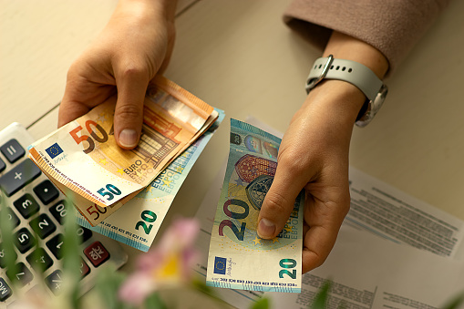 hands of a young woman with banknotes, counting money, summing up expenses for the trimester, heating period, rise in price of utilities, financial crisis, growth