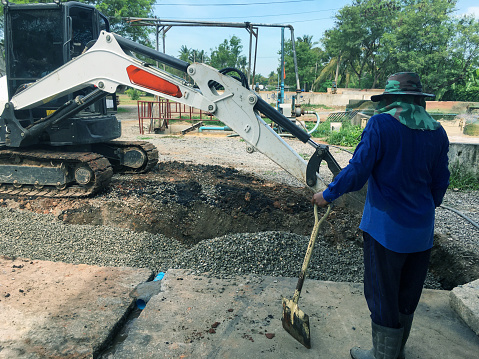 Construction worker steering a backhoe to renovate the site in preparation for pouring the concrete slab.
