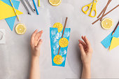 Paper lemonade with lemons. Children at home. Hands making DIY summer crafting. Kindergarten ideas step by step.