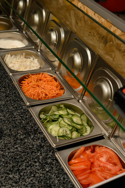 istock Dishes for ready-made chopped vegetables on the surface of a work table in a fast food restaurant 1519118061