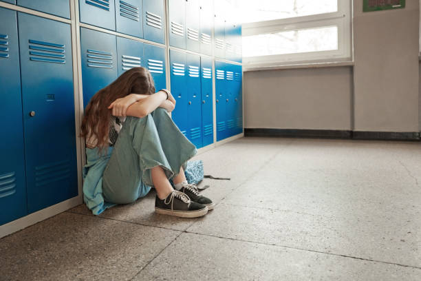 besorgtes teenager-mädchen sitzt in der schule auf dem boden - schoolgirl teenager teenage girls teenagers only stock-fotos und bilder
