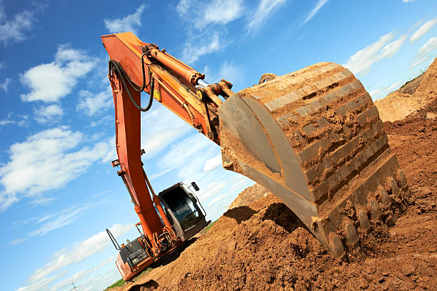 Angled photo of excavator arm digging in a dirt pile track-type loader excavator machine doing earthmoving work at sand quarry Earthmoving stock pictures, royalty-free photos & images