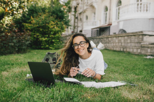 istock Young woman student studying using her books, laptop and notebook, sitting on grass. 1519148678