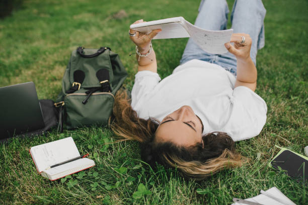 istock Young woman student studying using her books, laptop and notebook, sitting on grass. 1519148680