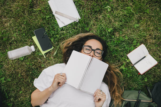 istock Young woman student studying using her books, laptop and notebook, sitting on grass. 1519148847