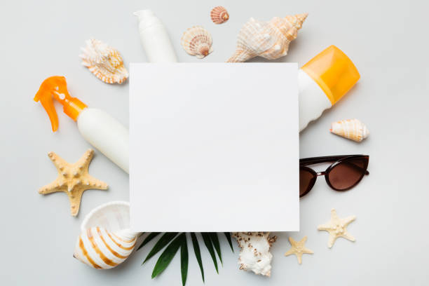 istock Summer time concept with blank greeting card and blank white paper on colored background. Seashells from ocean shore in the shape of frame separated with space for text top view 1519157941