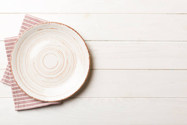 istock Top view on colored background empty round white plate on tablecloth for food. Empty dish on napkin with space for your design 1519158487