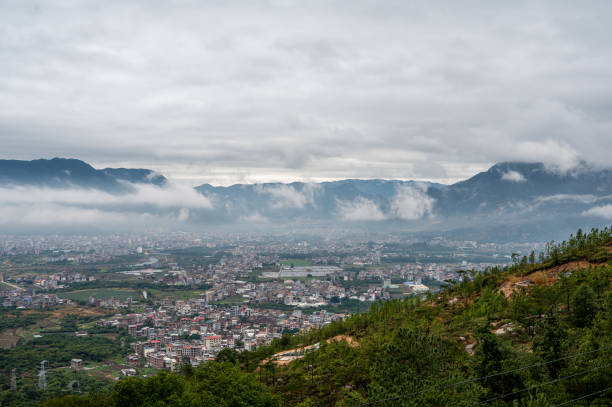 cidade sob a montanha sob a chuva - meteorology rain fog forest - fotografias e filmes do acervo