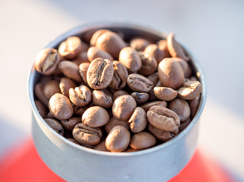 Roasted coffee beans in a funnel with coffee powder