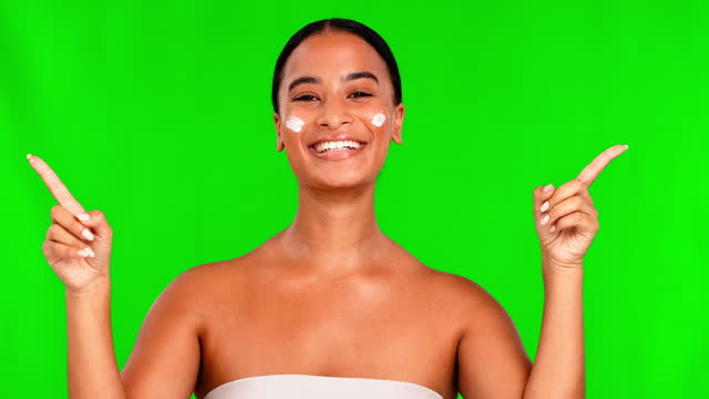 Face, green screen and woman with lotion, pointing and selection with salon treatment, grooming and beauty. Portrait, female person and model with dermatology, choice and cream on a studio background