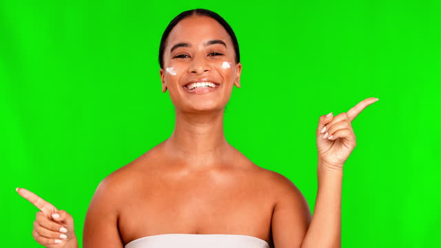 Face, green screen and woman with cream, pointing and beauty with a choice, skincare and decision. Portrait, female person or model with selection, lotion and dermatology against a studio background