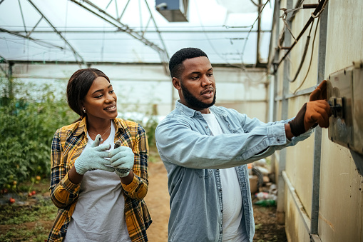 Man and a woman regulate everything to be good in the greenhouse