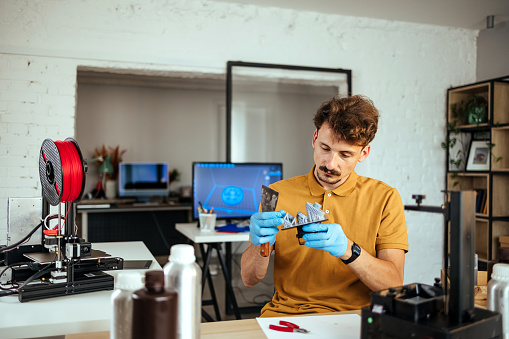Man repairs a 3D printer in his home office