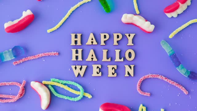 4k zoom in out Halloween concept. Halloween party decorations with words Happy Halloween, sweets, top view flat lay on blue background