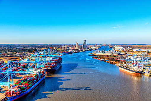 Mobile, United States - January 31, 2022:  The Port of Mobile, the industrial waterfront and shipyards at the Port of Mobile, Alabama with a view up the Mobile River showing the downtown skyline in the distance  shot from an altitude of about 600 feet overhead.