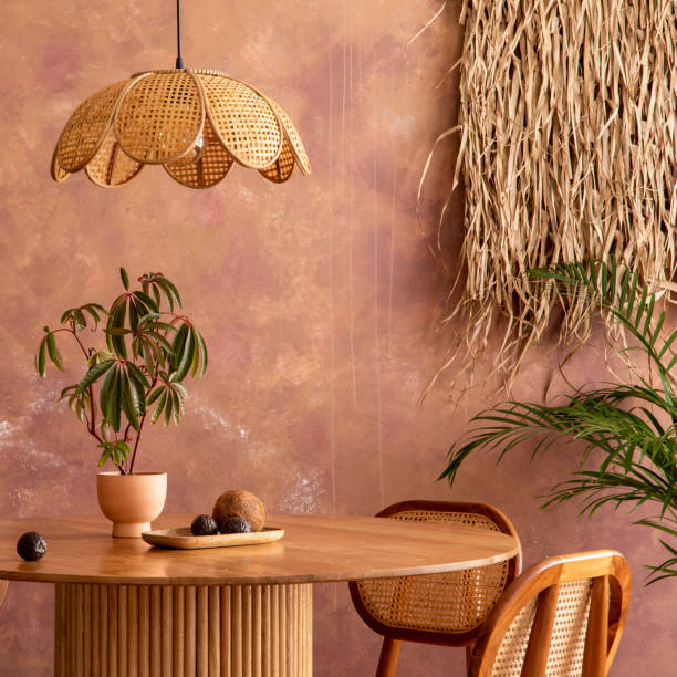 istock Boho vintage dining room interior with round table, rattan chair, commode and flowers. Brown wall and rattan lamp. Mock up poster. Template. 1519355503