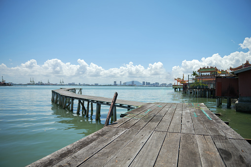 A vintage wooden bridge extends into the sea against blue sky background. Selective focus.