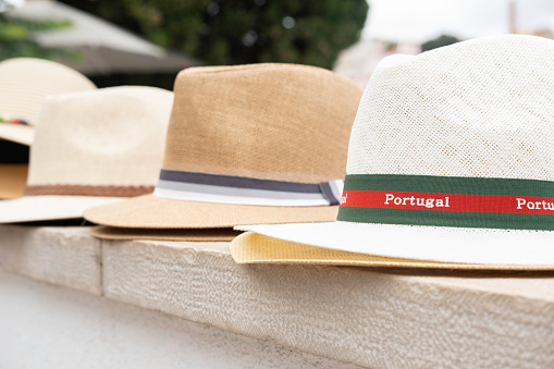 A local market selling a variety of hats with Portugal text.