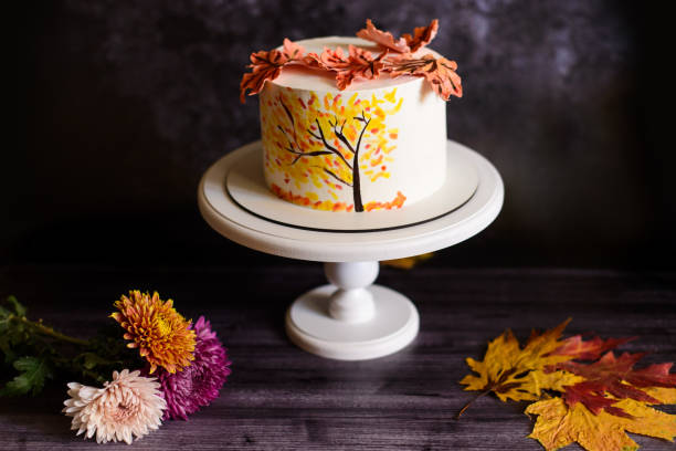 istock a cake with an autumn pattern next to chrysanthemums, on a white stand and a dark background 1519365513