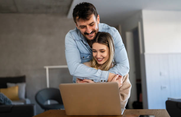 istock Cheerful young couple using laptop and smiling while shopping online at home 1519367979