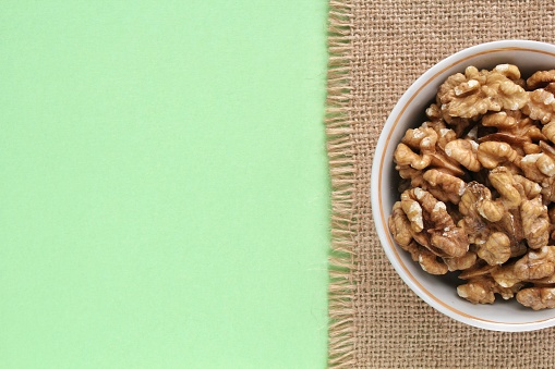 Walnuts on canvas and green background. Healthy diet, nutrition, vegan concept. Protein dry organic snack. Raw food