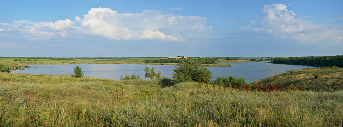 Panoramic view of the rural landscape. Blooming meadow and tortuous river in the late afternoon.