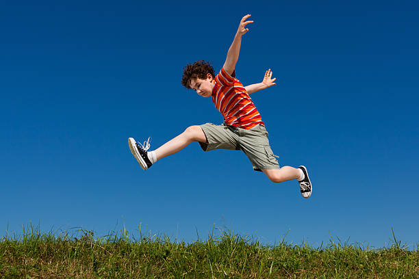 garçon sauter contre le ciel bleu - pre teen boy photos et images de collection