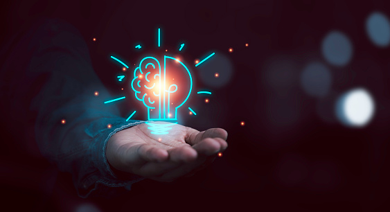 Hand holding drawing virtual lightbulb with brain on bokeh background for creative thinking idea and innovation concept.