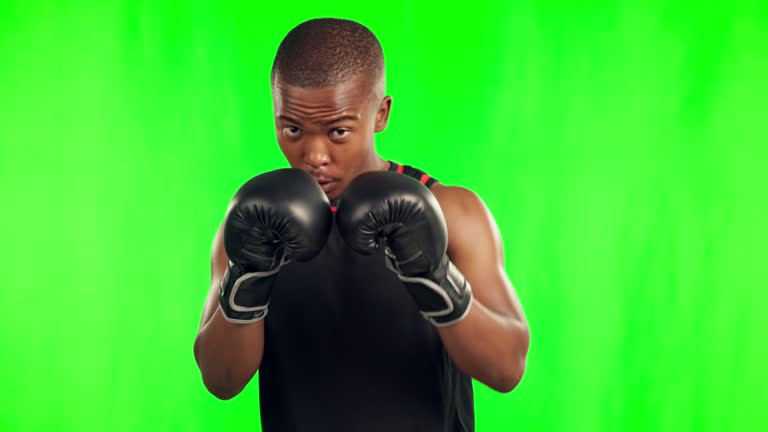 Black man, boxer and punching in fight on green screen against a studio background. Portrait of African male person or fighter with boxing gloves in sports exercise, workout or training on mockup