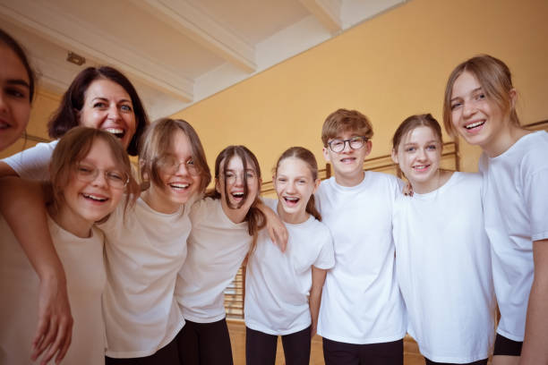 Group Of Excited Elementary School Pupils Wearing Uniform Having Fun Against Red Studio Background