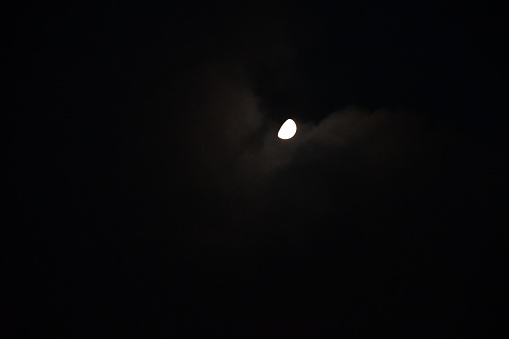 A bright white moon comfortable with being seen in a sea of darkness in the black sky.