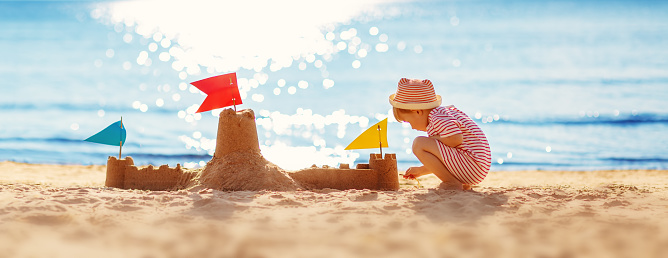 Little boy building sand castle on the sea beach. Concept of the family vacation and tourism.