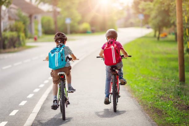Two boys with backpacks on bicycles going to school. stock photo