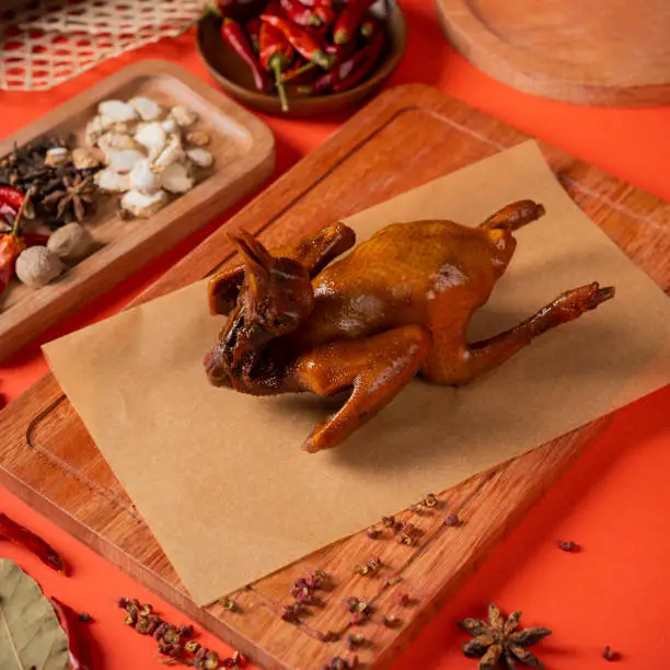 Photo of Pigeon meat marinated with spices, Chinese specialty food, shot in the kitchen, dark background, with various spices